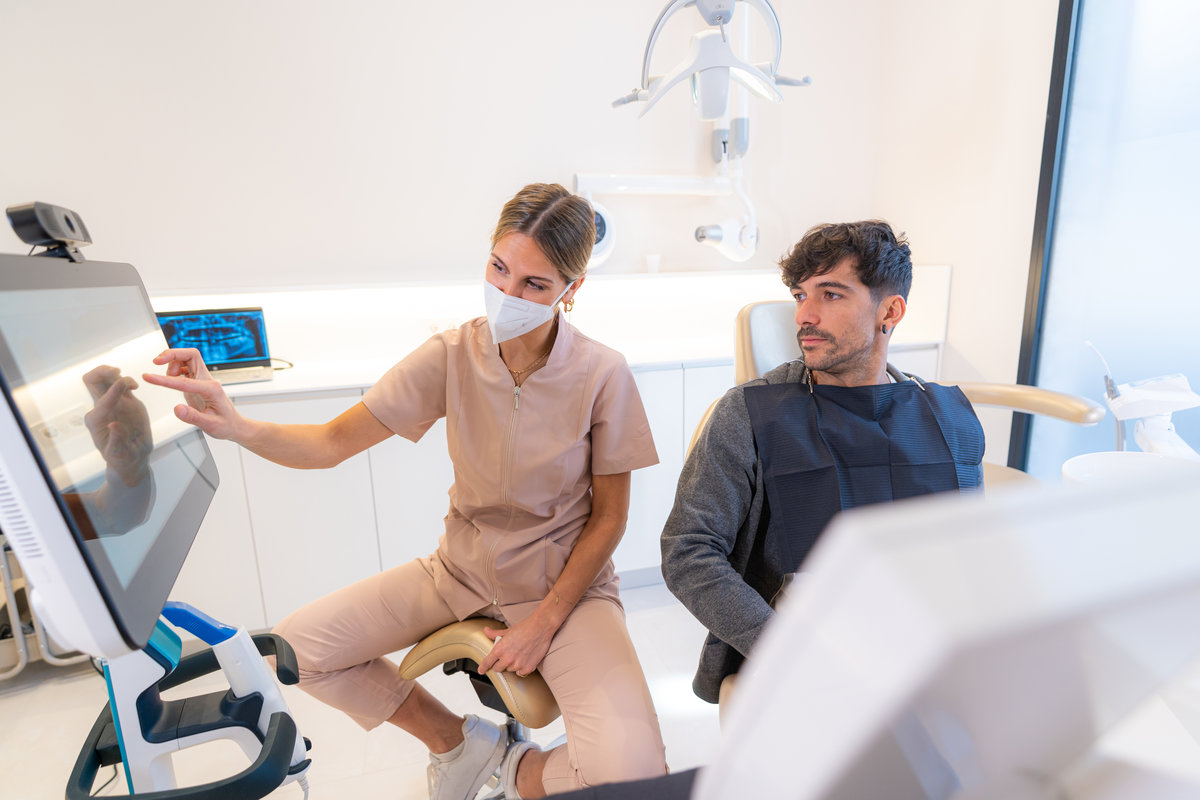 Dentist showing multidimensional image to patient sitting on a chair in a modern clinic